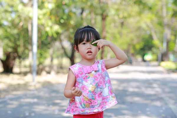 Porträt eines süßen kleinen Mädchens im öffentlichen Park mit lustigem Gesicht und Haltung mit Blatt — Stockfoto