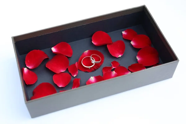 Anillos de boda en pétalos de rosa roja en caja de cuero de lujo . — Foto de Stock