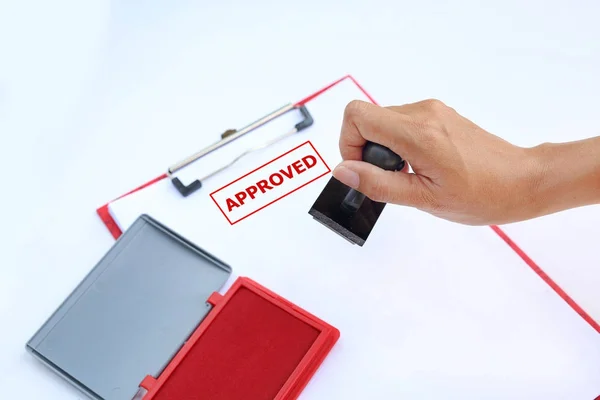 Közelkép kezét bélyegzés jóváhagyott papír lapot, a vörös tinta pad(box) fehér háttér. — Stock Fotó