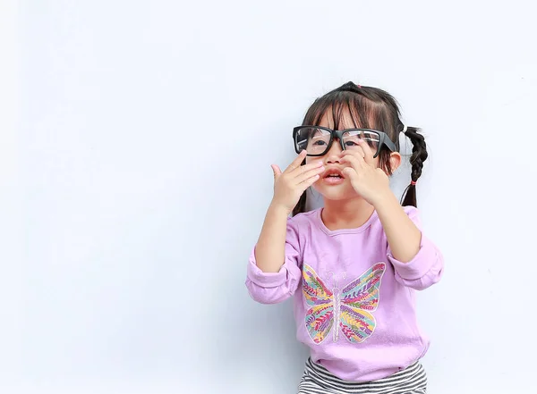 Πορτρέτο του χαριτωμένο μικρό κορίτσι που προσπαθεί να φορέσει γυαλιά σε λευκό φόντο — Φωτογραφία Αρχείου