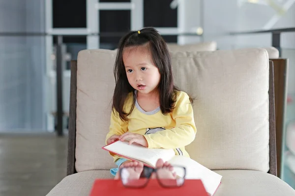 Kleine kind meisje leesboek in bibliotheek, onderwijs concept. — Stockfoto