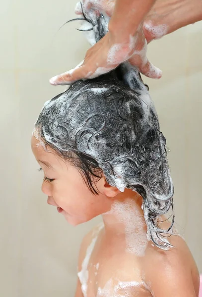 Gadis kecil yang lucu mencuci rambut di bak mandi gelembung . — Stok Foto