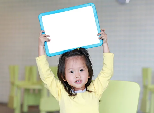 Mignon asiatique enfant fille tenue vide blanc tableau dans salle de jeux . — Photo