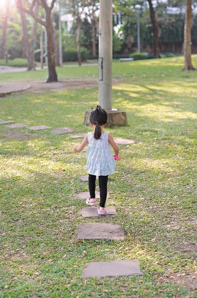 Vista trasera niña caminando por el camino de piedra en el jardín por la mañana —  Fotos de Stock