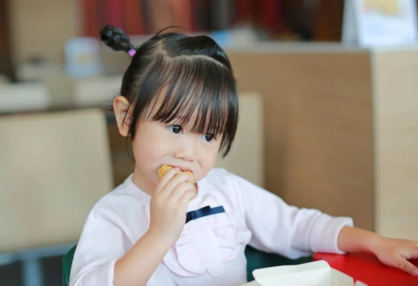 Крупным планом маленькая азиатская девочка ест жареную курицу в кафе . — стоковое фото