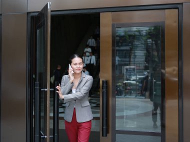 Açık kapı ile telefon kullanarak ve dışında yürüyüş güzel genç iş kadını.