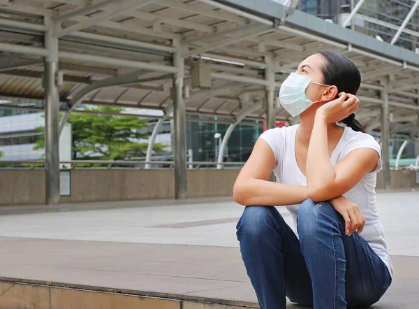 Kirliliği ve genel bölgede oturan grip korumak için koruyucu maske giyen kadın.