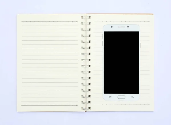 Smartphone su notebook aperto su sfondo bianco — Foto Stock