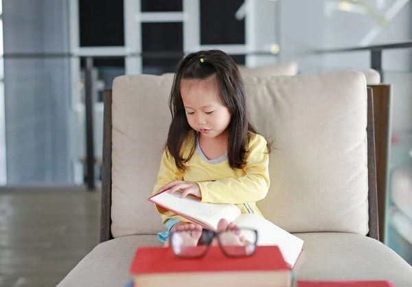 Kleine kind meisje leesboek in bibliotheek, onderwijs concept. — Stockfoto