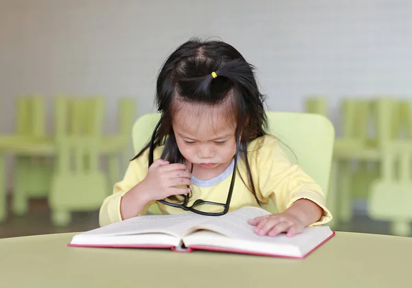 Slim meisje kind met glazen plan lezen van een boek in de kinderkamer. — Stockfoto