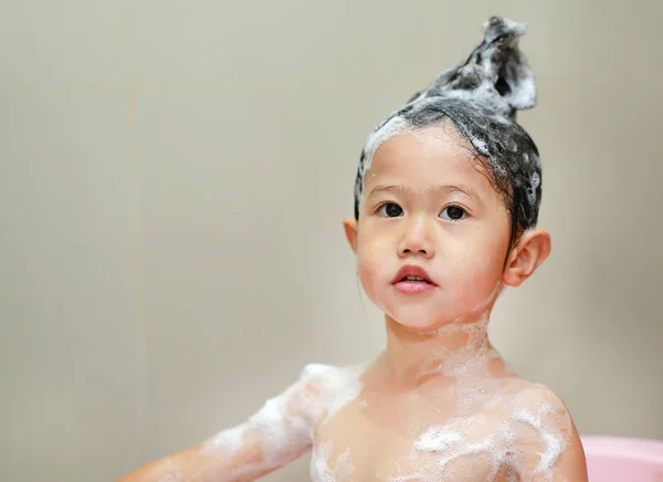 Χαριτωμένο μικρό παιδί κορίτσι πλύσιμο των μαλλιών στο λουτρό φυσαλίδων. — Φωτογραφία Αρχείου