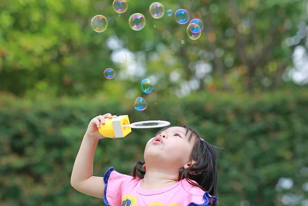 Милая маленькая девочка, играющая в пузырь в парке . — стоковое фото