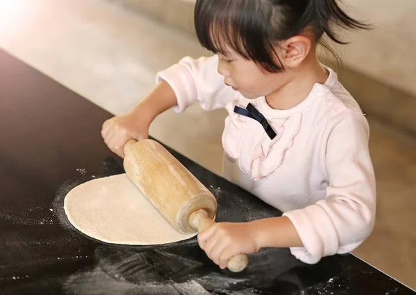 Nettes kleines Mädchen mit hölzernem Nudelholz auf Teig für Pizza. hausgemachte Zubereitung von Pizza. — Stockfoto