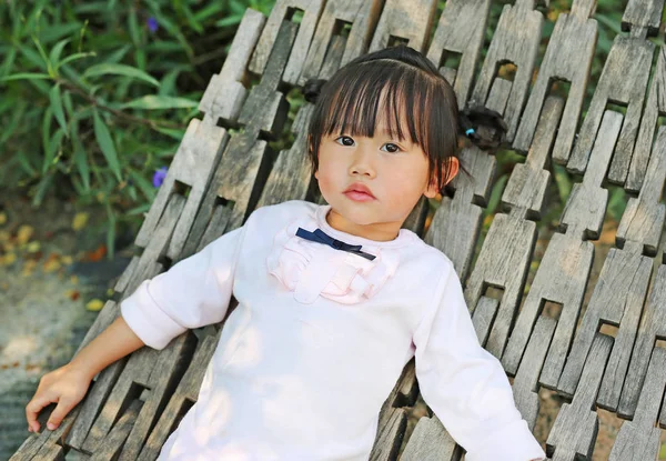 Kleines Mädchen liegt auf Holzwiege im Garten — Stockfoto