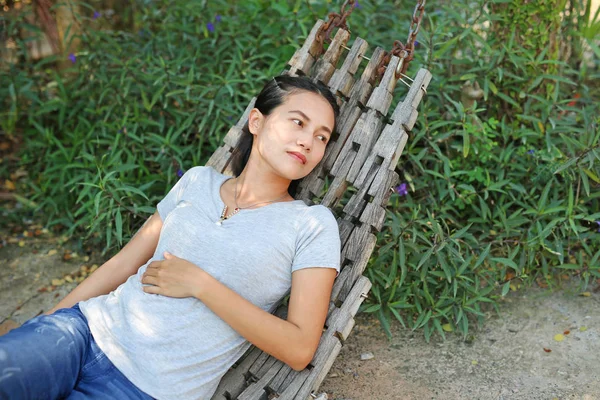 Mladá žena ležící na dřevo kolébky v zahradě — Stock fotografie