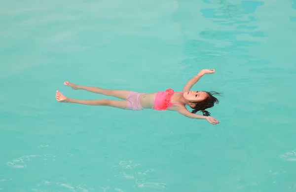 수영장의 물 표면에 떠 있는 어린 소녀 — 스톡 사진