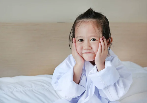 Μικρό παιδί κορίτσι στο κοστούμι του γιατρού ξαπλωμένη στο κρεβάτι — Φωτογραφία Αρχείου
