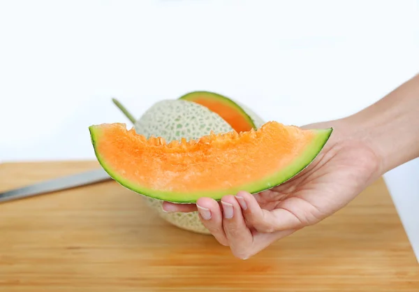 Meloun plátky melounu v ruce na dřevěné desce — Stock fotografie
