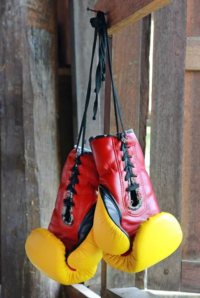 Paar rot-gelbe Boxhandschuhe hängen auf Holz. — Stockfoto