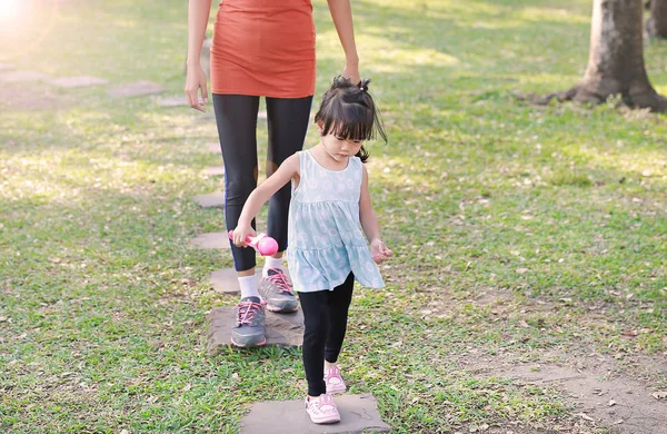 Mother and her daughter walking on stone pathway in the garden at the morning — Stock Photo, Image