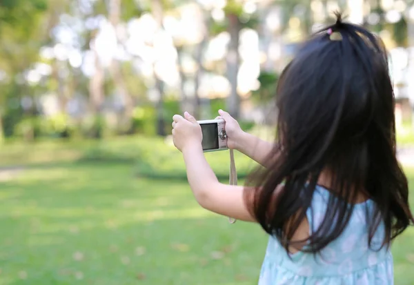 Child girl taking pictures on camera in the garden — Stock Photo, Image