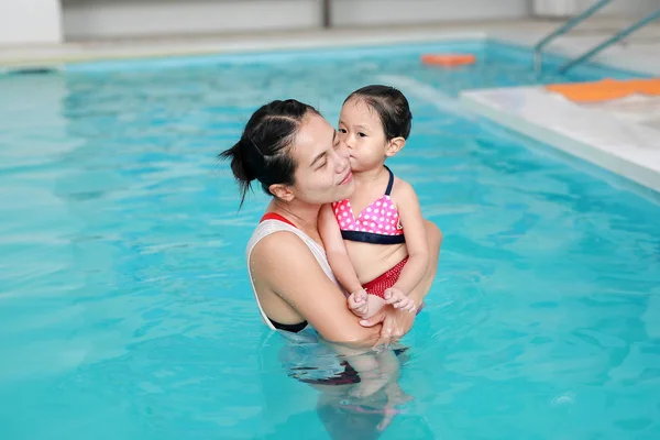 Felice sorridente asiatica bambina con madre nuotare in piscina d'acqua — Foto Stock