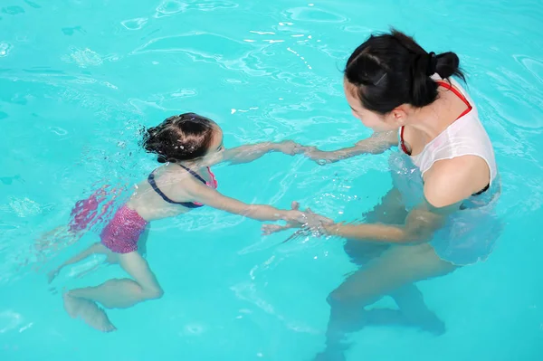 Close up mãe ensinando criança na piscina — Fotografia de Stock