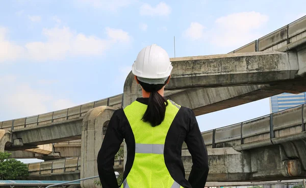 Back view of female construction worker against expressway background
