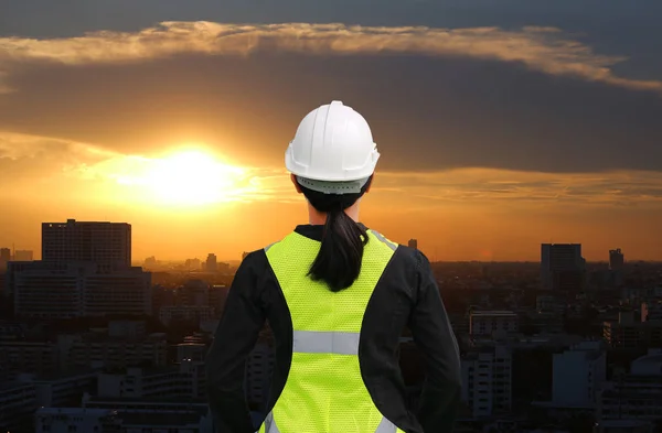 Vista trasera de la trabajadora de la construcción contra la construcción al atardecer en el fondo de la ciudad de Bangkok — Foto de Stock