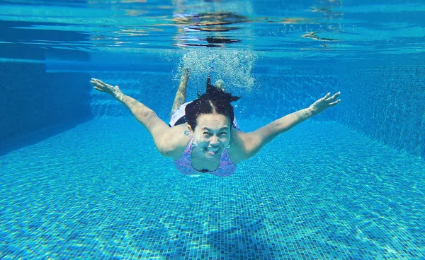 Foto subaquática de uma jovem mulher mergulhando na piscina . — Fotografia de Stock