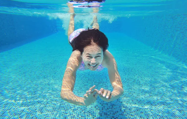 Foto subaquática de uma jovem mulher mergulhando na piscina . — Fotografia de Stock