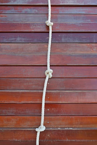Corda branca amarrada em um nó e prancha de madeira para aventura . — Fotografia de Stock