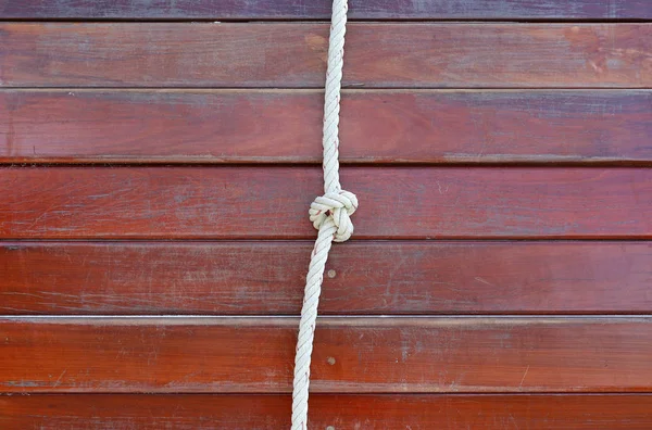 Cuerda blanca atada en un nudo y tablón de madera para la aventura . — Foto de Stock