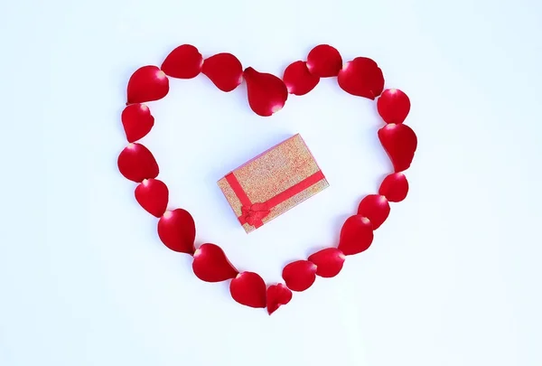 Pétalos de rosa roja en forma de corazón con caja de regalo aislada sobre fondo blanco . — Foto de Stock