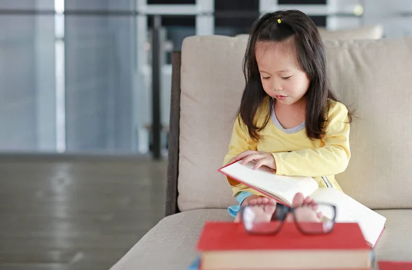 Kleine kind meisje leesboek in bibliotheek, onderwijs concept. — Stockfoto