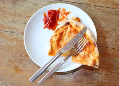 Parça pizza plaka üzerinde kalır. Yemek atıkları.