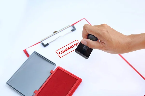 Gros plan Estampage à la main Garantie sur feuille de papier avec tampon d'encre rouge (boîte) sur fond blanc . — Photo