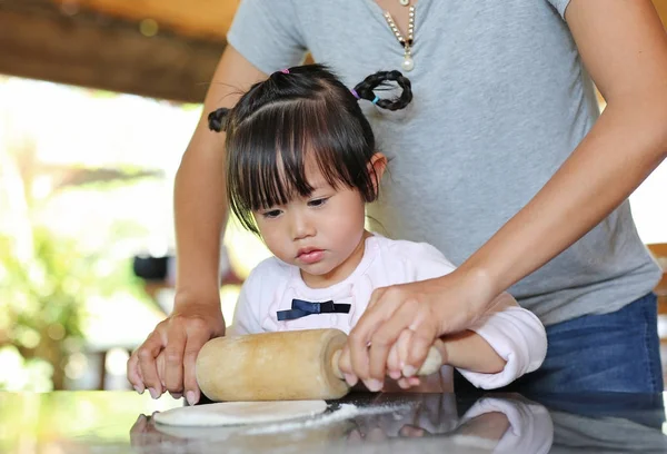 Anya és aranyos kislány, segítségével a fából készült járművek pin tésztát a pizza. Házi pizza előkészítő folyamat. — Stock Fotó