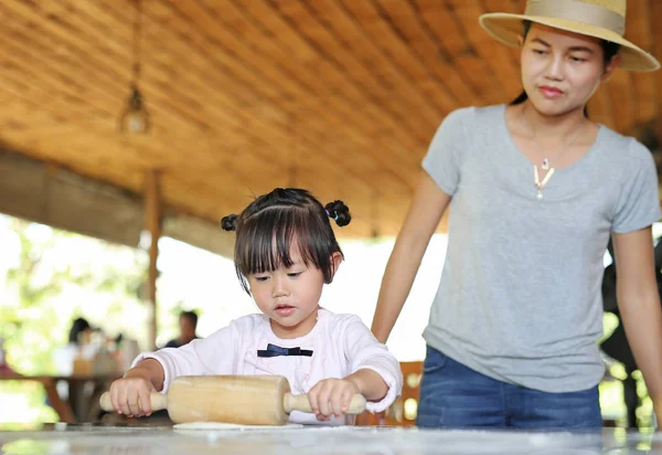 Anya és aranyos kislány, segítségével a fából készült járművek pin tésztát a pizza. Házi pizza előkészítő folyamat. — Stock Fotó
