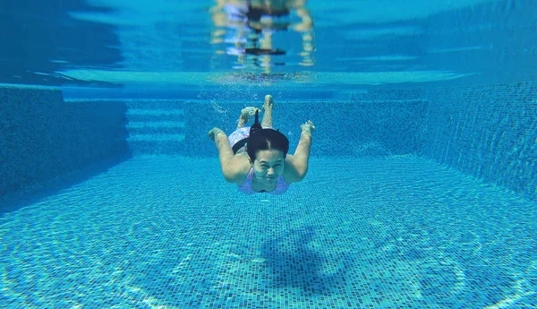 Unterwasseraufnahme einer jungen Frau, die ins Schwimmbad springt. — Stockfoto
