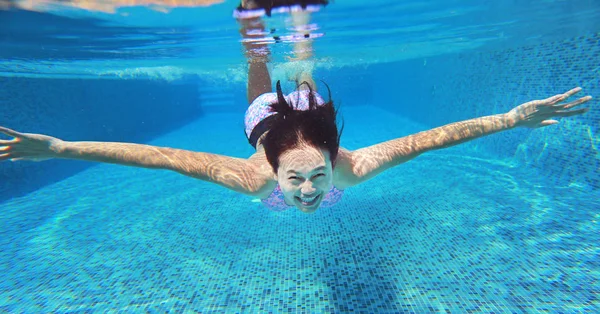 Подводный кадр молодой женщины, ныряющей в бассейн . — стоковое фото