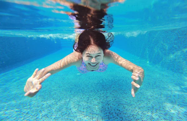 Foto subaquática de uma jovem mulher mergulhando na piscina . — Fotografia de Stock