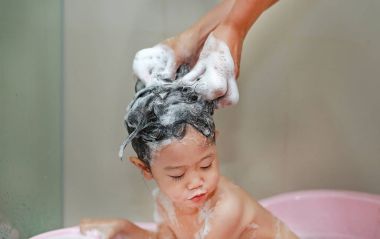 Annenin el duş küçük kızın saç yıkamak için su dökülen