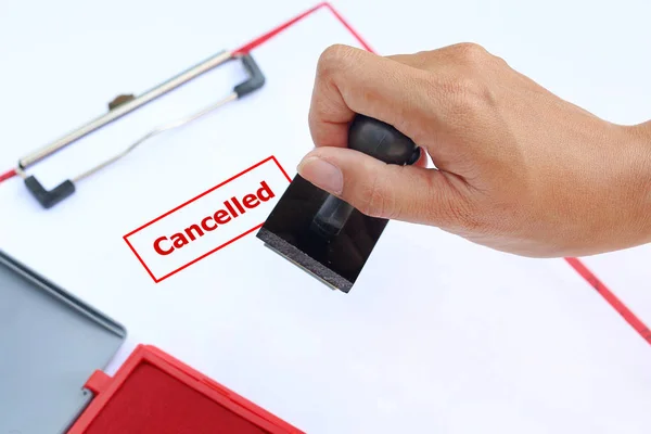 Close-up hand Stamping Cancelled on paper sheet with red Ink pad(box) against white background. — Stock Photo, Image