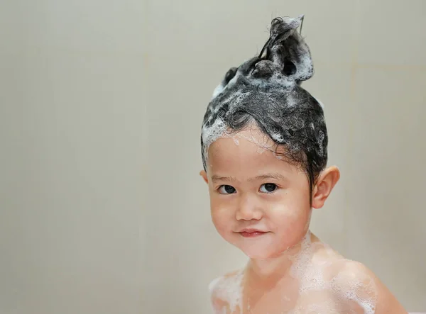 Μικρό κορίτσι κολύμβησης και πλύσιμο των μαλλιών στο λουτρό φυσαλίδων. — Φωτογραφία Αρχείου