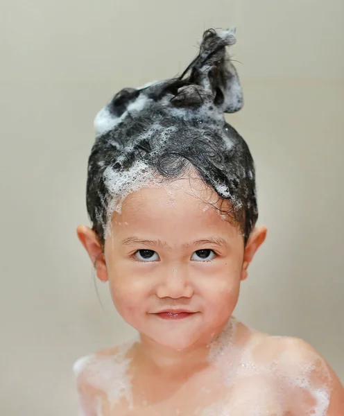 Маленькая девочка купается и моет волосы в ванне с пеной . — стоковое фото