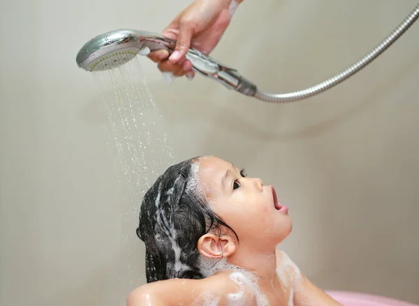 Mammas hand häller vatten från dusch för att tvätta lilla flickans hår — Stockfoto