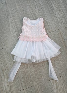 Ahşap arka plan üzerinde pembe-beyaz dantel elbise