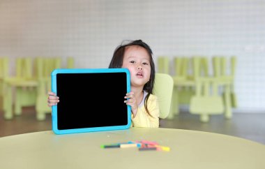 Boş yazı tahtası odasında tutan şirin Asyalı çocuk kız.