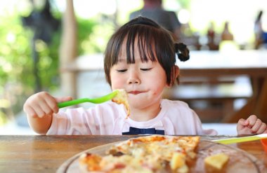 Küçük kız çocuk zevk pizza yemek.
